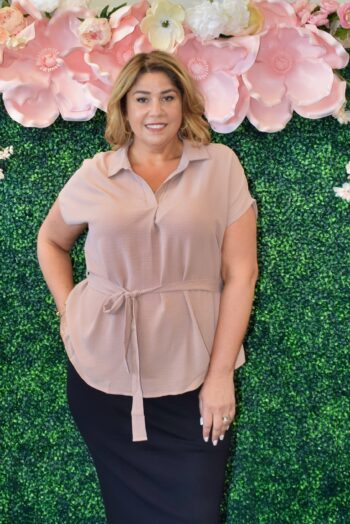 Curvy woman wearing a short sleeve collared blouse with a tie waist in taupe, blush, and white, perfect for plus size casual or office wear, available at Botticelli RI.