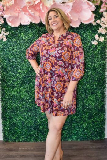 Woman wearing the Delilah Lizzy dress by Dear Scarlett in burgundy with roll-tab sleeves and a bold orange and purple floral print