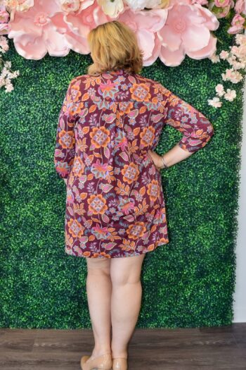 Woman wearing the Delilah Lizzy dress by Dear Scarlett in burgundy with roll-tab sleeves and a bold orange and purple floral print