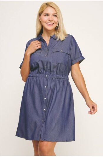 Woman wearing a silky chambray shirt dress in dark wash with front buttons, short sleeves, and elastic waist