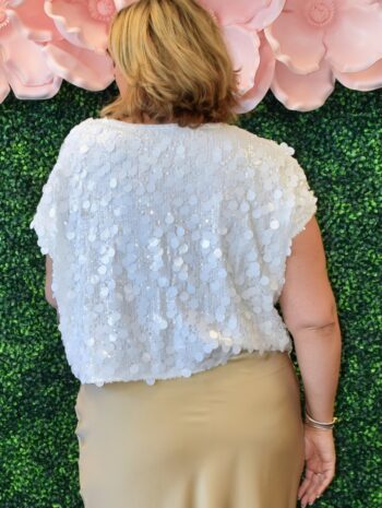 Back view of woman wearing white short sleeve sequin top with oversized shimmer detail – party-ready, size inclusive fit.