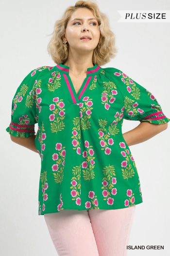 Plus-size model wearing a green floral blouse with pink trim and relaxed sleeves