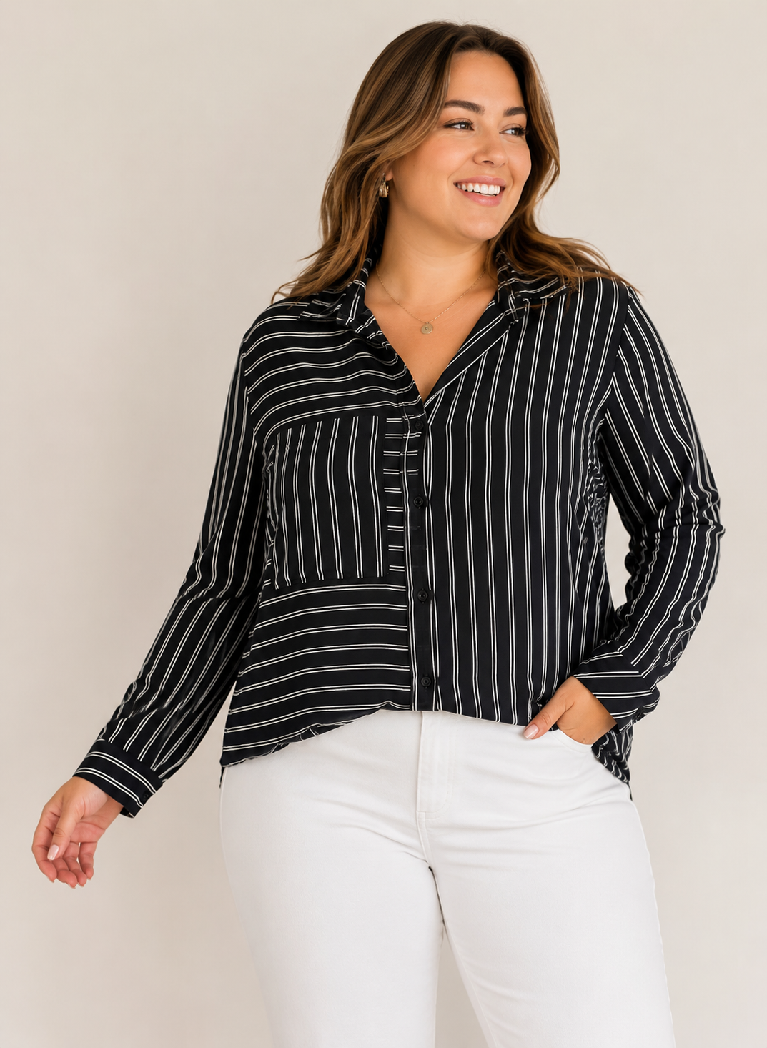 Curvy woman wearing a lightweight silky black stripe button-down blouse styled with white pants for polished casual outfits.