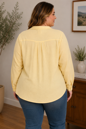 Back view of a lemon yellow blouse with long sleeves, lightweight texture, and curved hemline.
