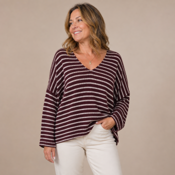 Mid-size woman wearing the Cabernet Stripe Sweater featuring a relaxed fit, burgundy and ivory stripes, V-neckline, and lightweight knit fabric.